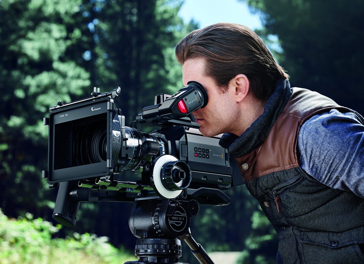 A man looking into the viewfinder of the Blackmagic URSA Mini cinema camera.