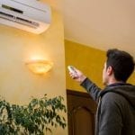 man-operating-air-conditioner-with-remote