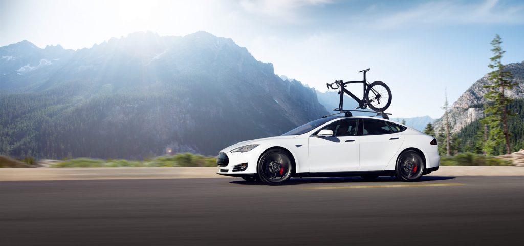 Tesla Model S with roof rails and a bike on top.