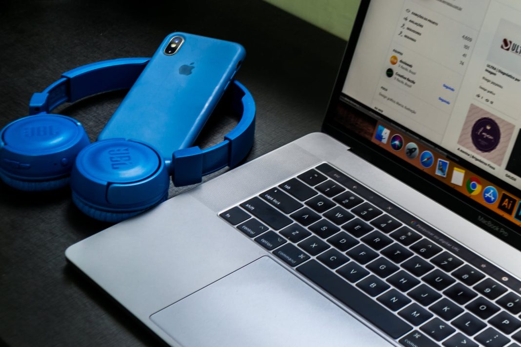 macbook pro beside blue wireless headphones